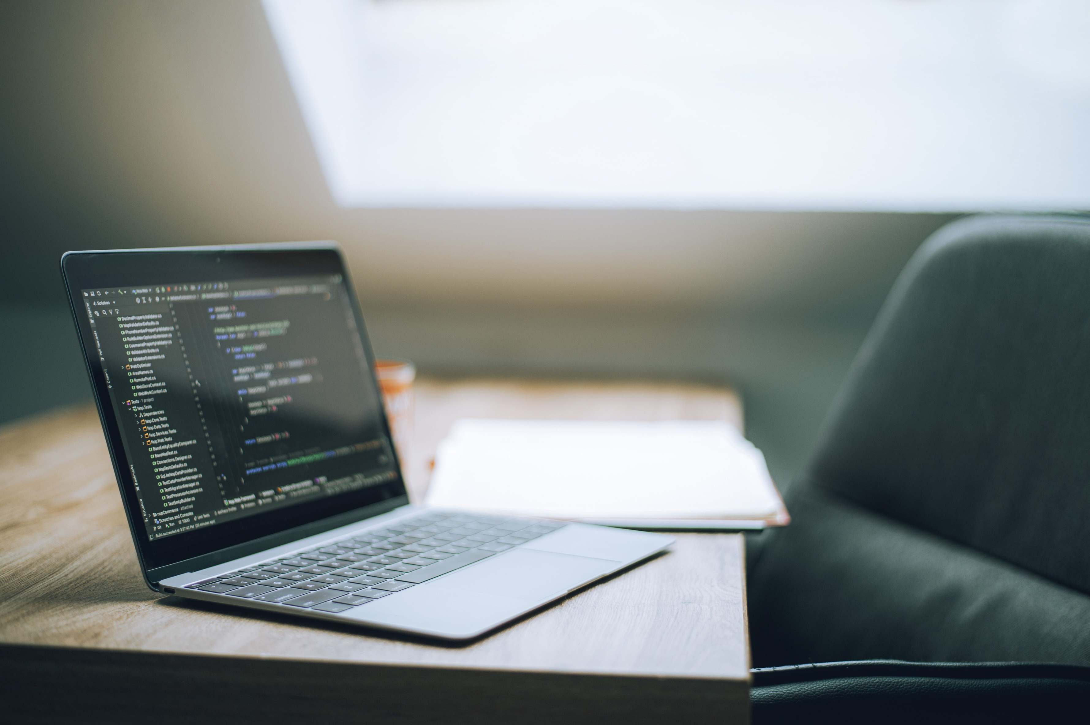 Laptop on a desk in a modern office workspace, developer typing code on a keyboard